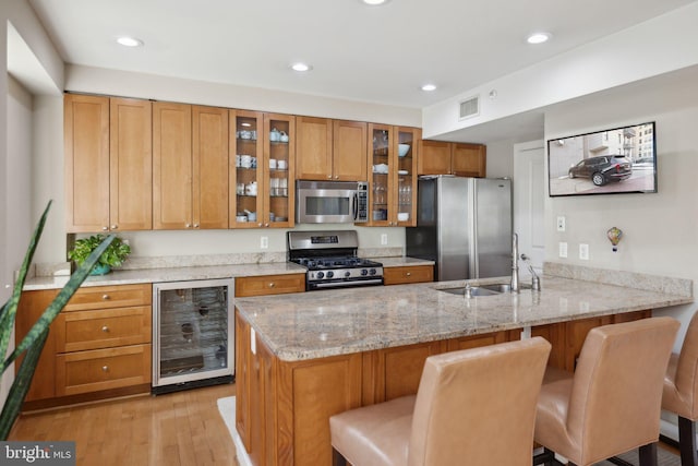 kitchen featuring beverage cooler, stainless steel appliances, sink, a kitchen breakfast bar, and kitchen peninsula