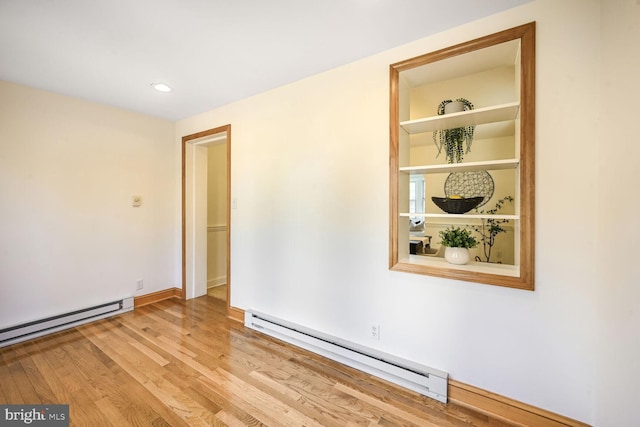 spare room with light wood-type flooring, baseboards, and a baseboard heating unit