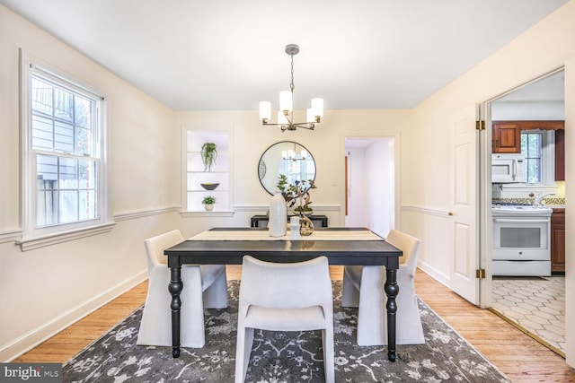 dining area with baseboards, an inviting chandelier, and light wood-style floors