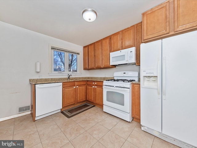 kitchen with light stone counters, white appliances, sink, and light tile patterned floors