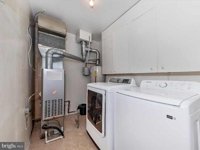 washroom featuring water heater, light tile patterned floors, washer and clothes dryer, and cabinets