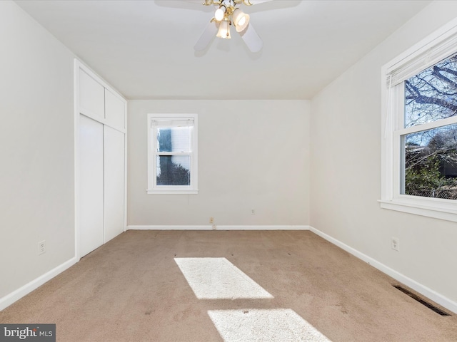 unfurnished bedroom with multiple windows, light colored carpet, and a closet