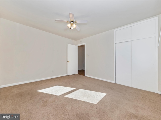 unfurnished bedroom featuring ceiling fan, a closet, and light carpet