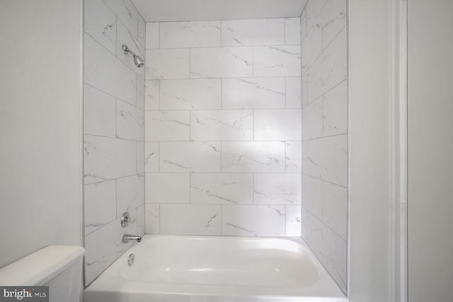 bathroom featuring tiled shower / bath combo and toilet