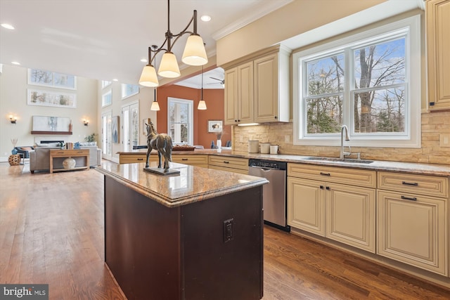 kitchen with hanging light fixtures, cream cabinets, open floor plan, a sink, and dishwasher