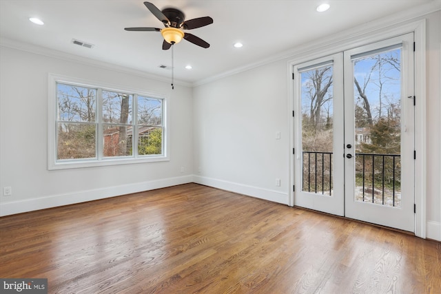 interior space featuring wood finished floors, visible vents, baseboards, ornamental molding, and french doors