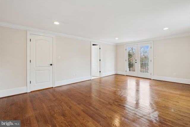 spare room with french doors, crown molding, baseboards, and wood finished floors