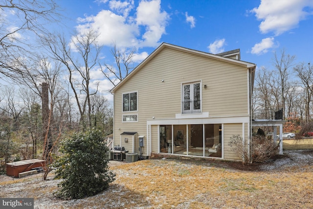 back of house with cooling unit, a sunroom, and a hot tub