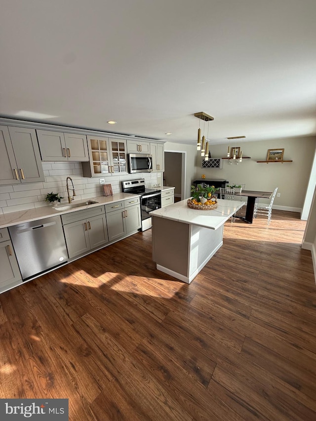 kitchen with sink, gray cabinets, hanging light fixtures, stainless steel appliances, and a kitchen island