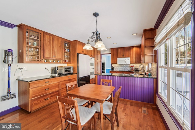 kitchen with an inviting chandelier, crown molding, refrigerator, dark hardwood / wood-style flooring, and pendant lighting