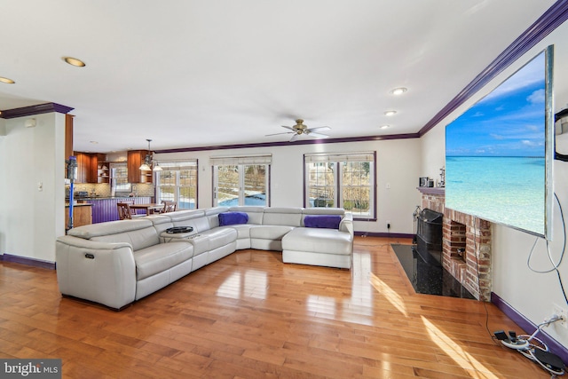 living room with crown molding, a fireplace, wood-type flooring, and plenty of natural light