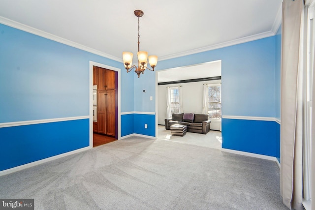 carpeted spare room featuring crown molding and an inviting chandelier