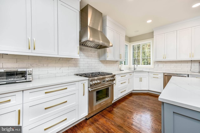 kitchen with wall chimney range hood, sink, stainless steel appliances, light stone counters, and white cabinets