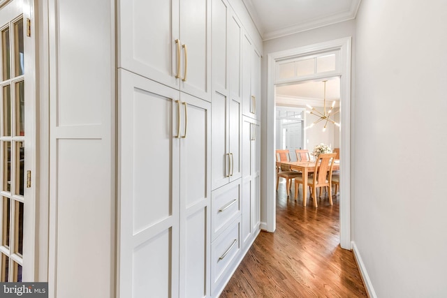 hall featuring crown molding, wood-type flooring, and a chandelier