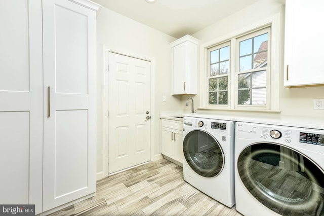 laundry room featuring cabinets, washer and clothes dryer, sink, and light wood-type flooring