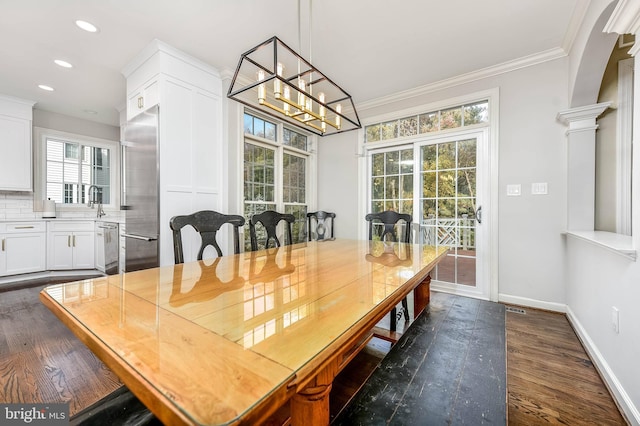 dining area with an inviting chandelier, ornamental molding, dark hardwood / wood-style floors, and ornate columns