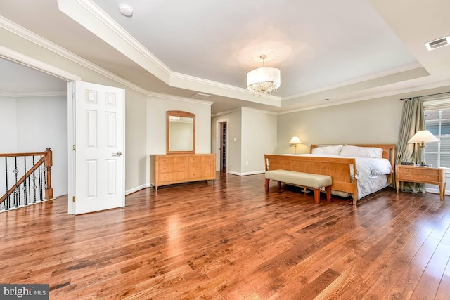 bedroom featuring a raised ceiling, ornamental molding, hardwood / wood-style floors, and a notable chandelier