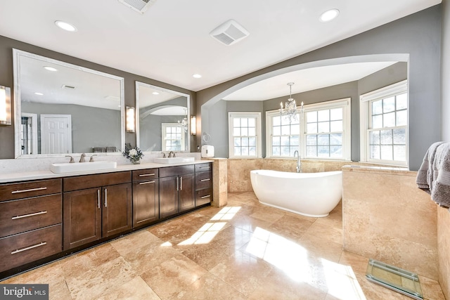 bathroom featuring vanity, tile walls, an inviting chandelier, and a tub to relax in