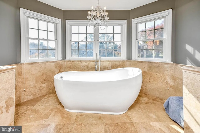 bathroom featuring a tub to relax in, a healthy amount of sunlight, and tile walls