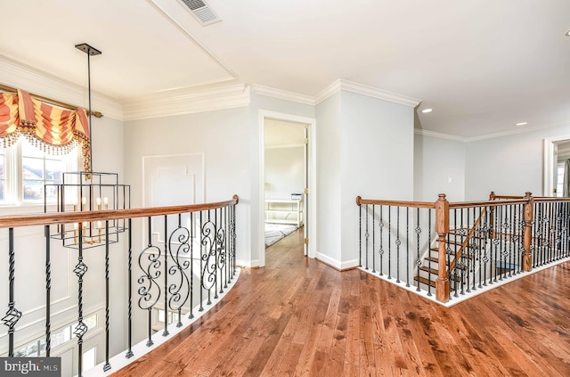 hallway featuring hardwood / wood-style flooring, ornamental molding, and a notable chandelier