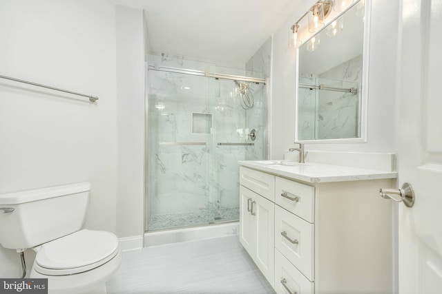 bathroom featuring vanity, toilet, and a shower with door