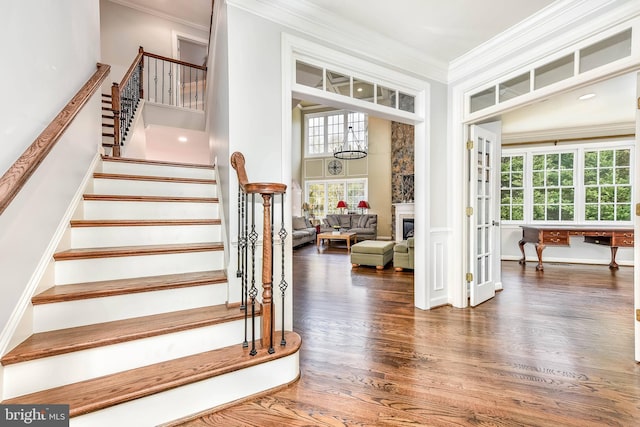 stairs featuring hardwood / wood-style flooring, ornamental molding, and a towering ceiling