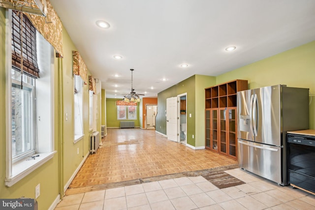 kitchen featuring radiator, dishwasher, hanging light fixtures, light parquet flooring, and stainless steel fridge