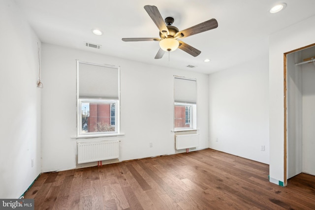 unfurnished bedroom with ceiling fan, hardwood / wood-style floors, and radiator