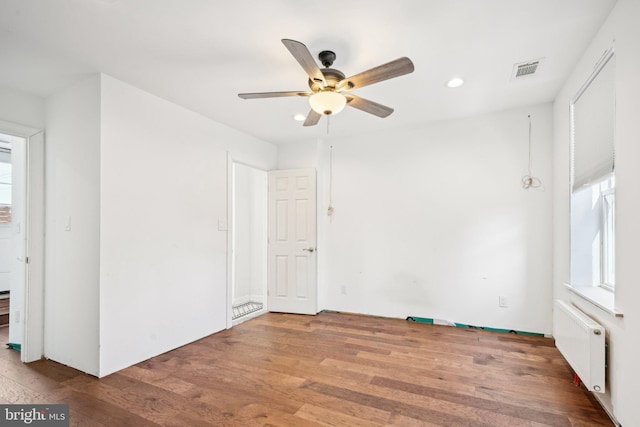 empty room featuring ceiling fan, hardwood / wood-style floors, and radiator