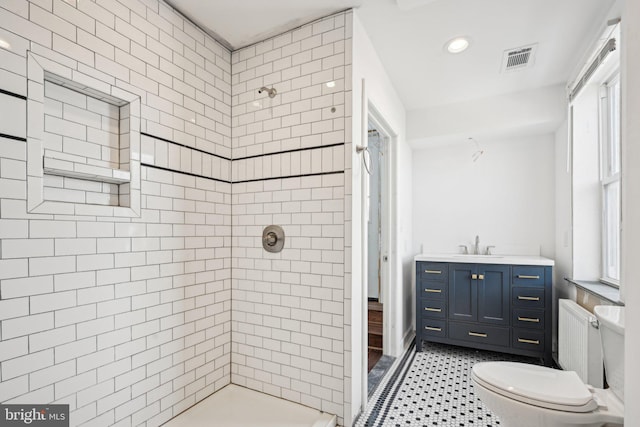 bathroom with toilet, radiator heating unit, a tile shower, and vanity