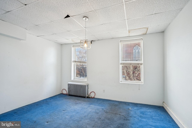 carpeted spare room featuring a drop ceiling and radiator