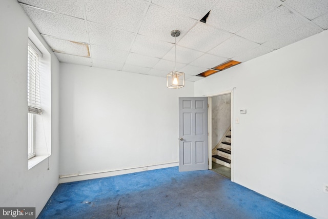 carpeted empty room featuring plenty of natural light and a drop ceiling