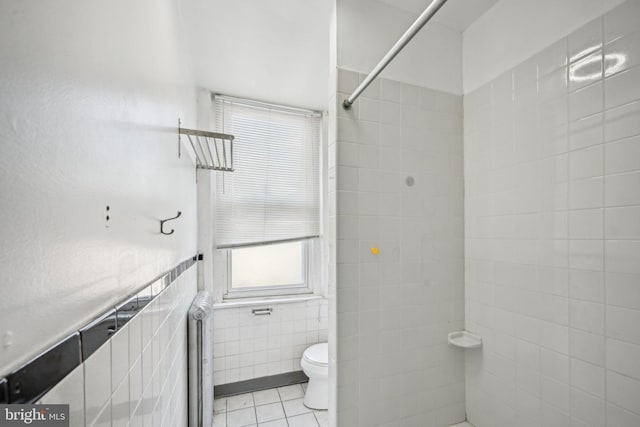 bathroom featuring plenty of natural light, radiator, tile patterned floors, and tile walls