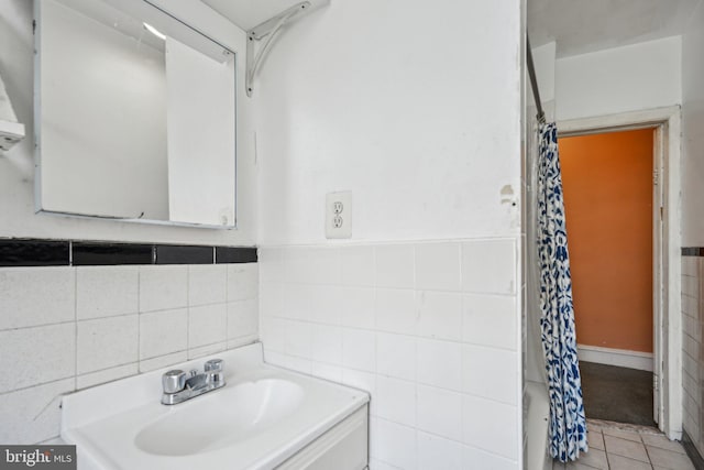 bathroom with curtained shower, tile patterned floors, and tile walls