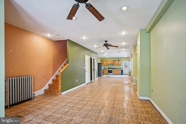 unfurnished living room featuring radiator heating unit, light parquet floors, and ceiling fan