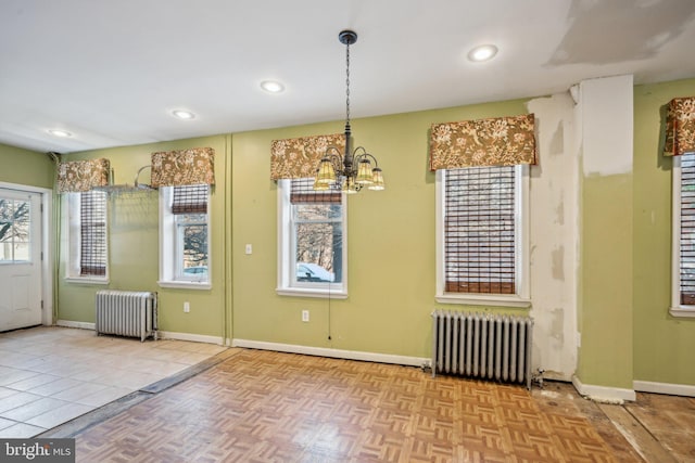 unfurnished dining area featuring radiator heating unit, an inviting chandelier, and light parquet flooring