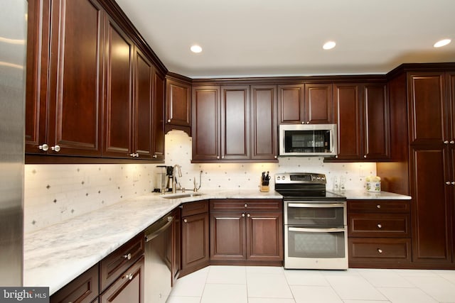 kitchen with stainless steel appliances, sink, light tile patterned floors, and backsplash