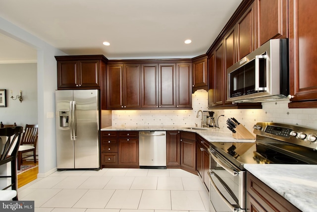 kitchen with crown molding, stainless steel appliances, light stone countertops, and sink