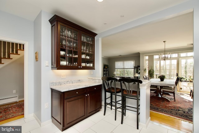 bar with light stone countertops, light tile patterned floors, dark brown cabinetry, and baseboard heating