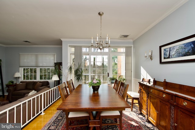 dining space featuring an inviting chandelier, crown molding, light hardwood / wood-style floors, and a wealth of natural light