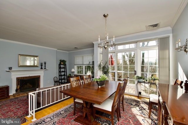 dining room with hardwood / wood-style flooring, a fireplace, a chandelier, and crown molding