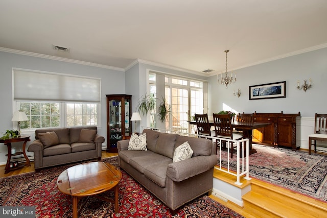 living room with hardwood / wood-style flooring, crown molding, a healthy amount of sunlight, and a chandelier