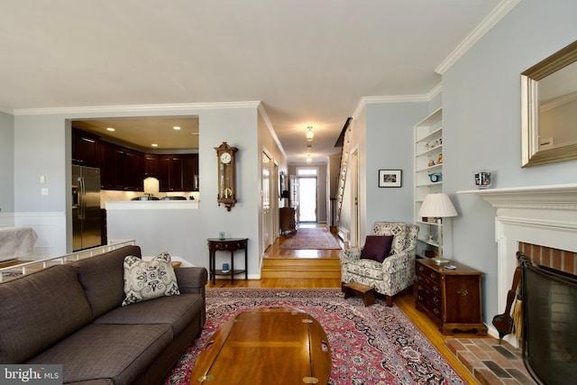 living room featuring ornamental molding, a brick fireplace, and light wood-type flooring