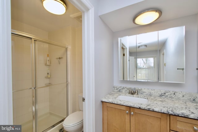 bathroom with vanity, toilet, and a shower with door