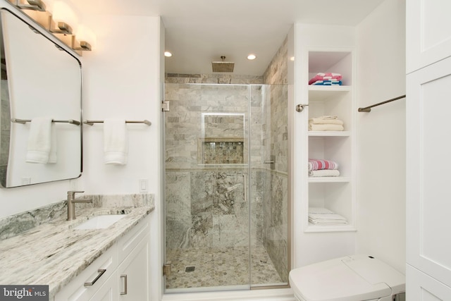 bathroom with vanity, built in shelves, a shower with shower door, and toilet