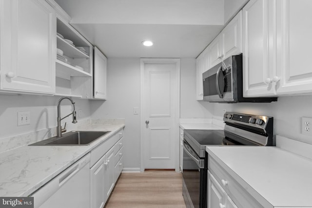 kitchen with sink, stainless steel appliances, light stone counters, light hardwood / wood-style floors, and white cabinets