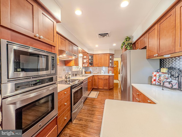 kitchen with light hardwood / wood-style floors, appliances with stainless steel finishes, tasteful backsplash, and sink