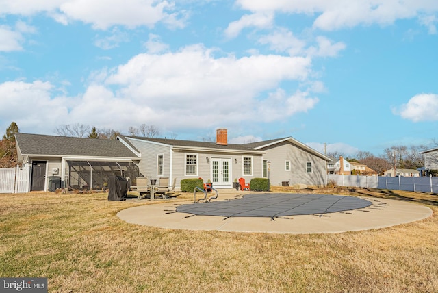 rear view of property with a covered pool, french doors, a sunroom, a yard, and a patio