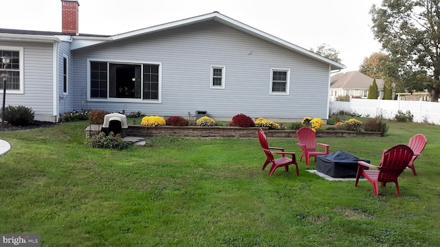 rear view of house with a fire pit and a lawn