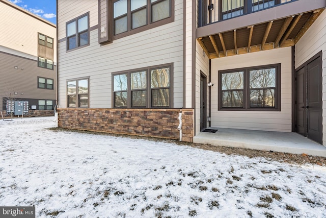 snow covered property entrance featuring a patio